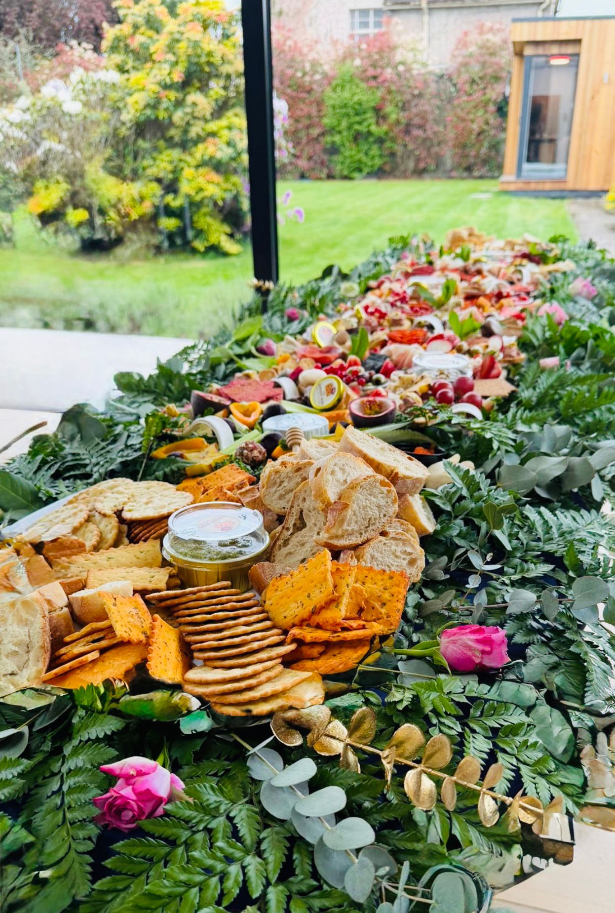 Garden-side grazing table with breads, crackers and pesto facing onto the lawn