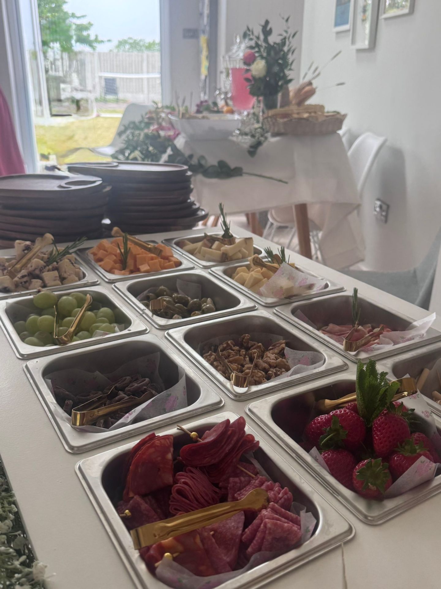 Stainless steel trays of cubed cheeses, charcuterie, strawberries and walnuts