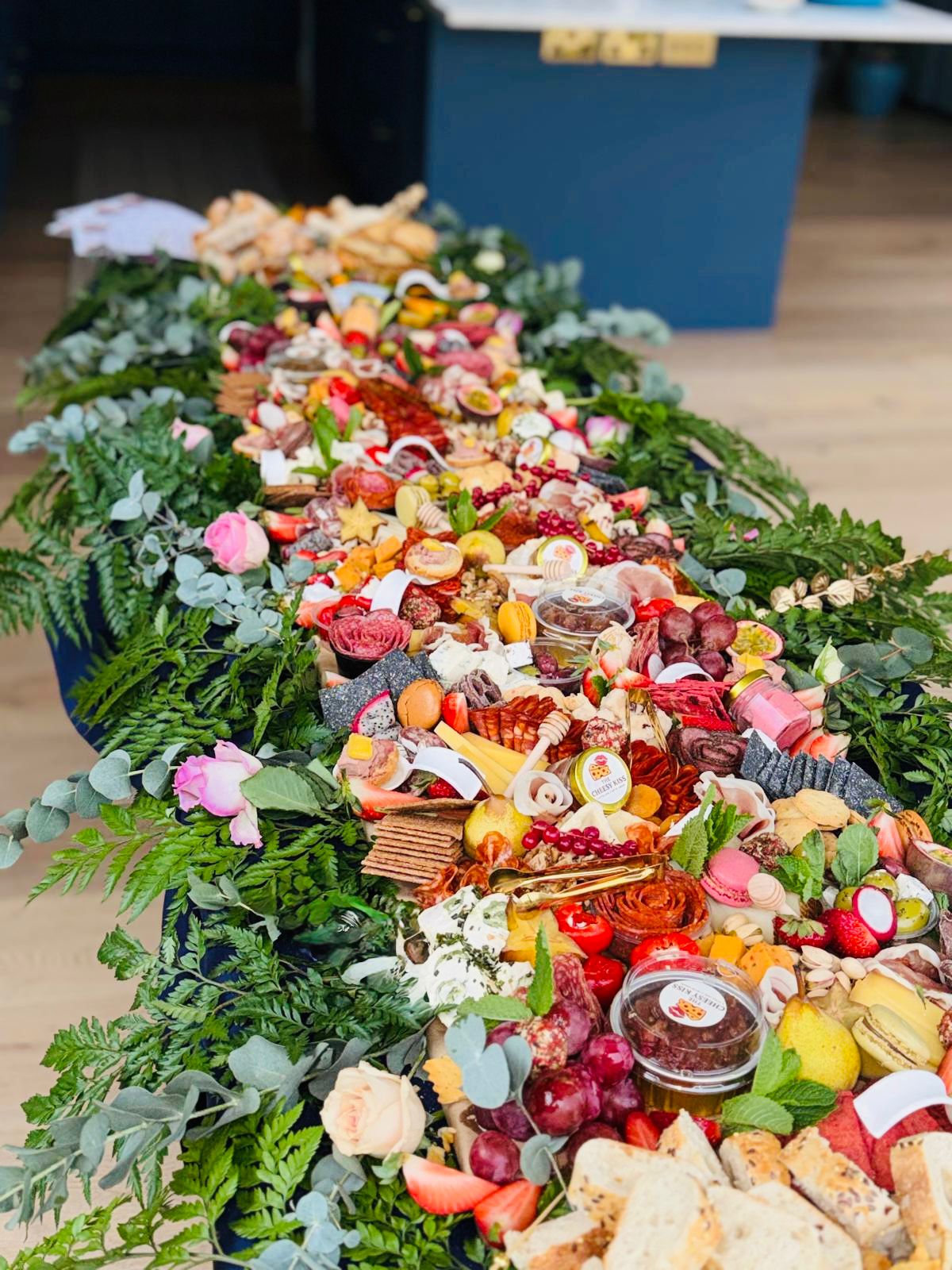 Long view of grazing table with salami roses, breads and dips framed by greenery