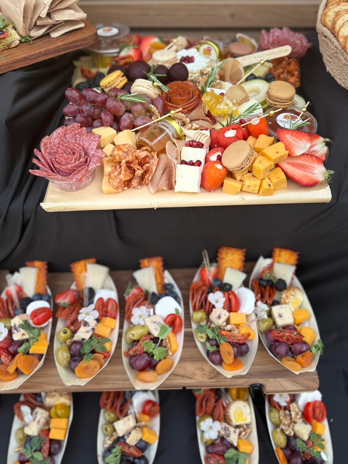 Charcuterie board with salami rose, macarons, cheeses and fruit, with individual grazing cones below
