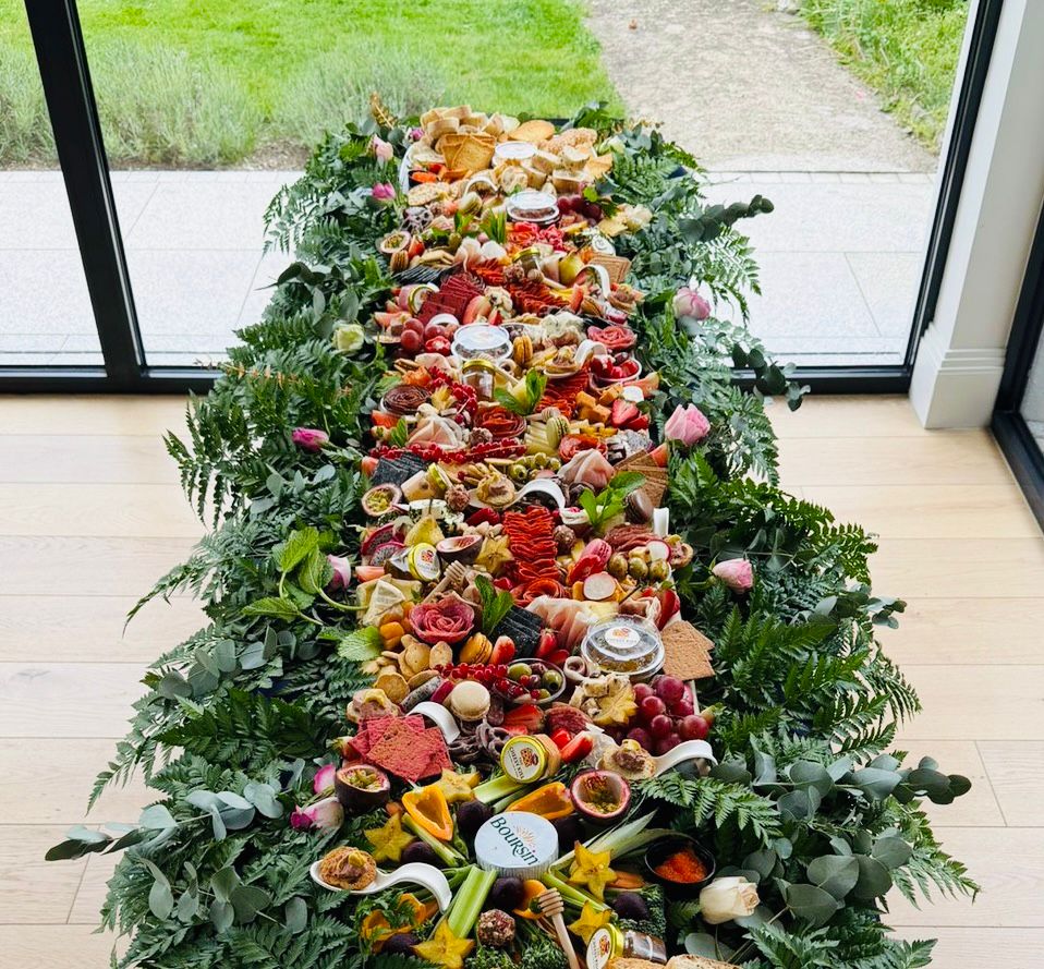 Overhead view of an 8ft flat grazing table styled with ferns, eucalyptus and roses