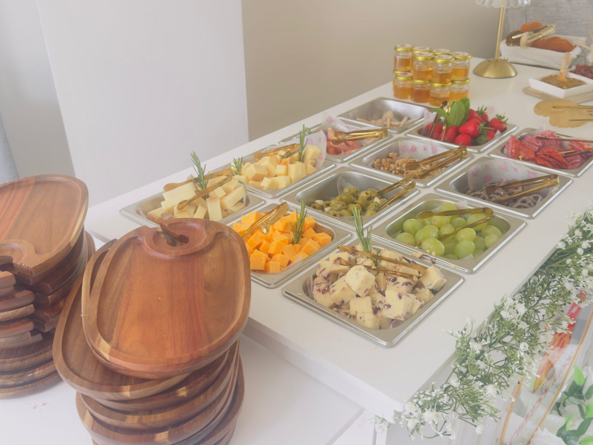 Build-your-own cheese station with cheeses, olives, fruits, honey jars and gold tongs